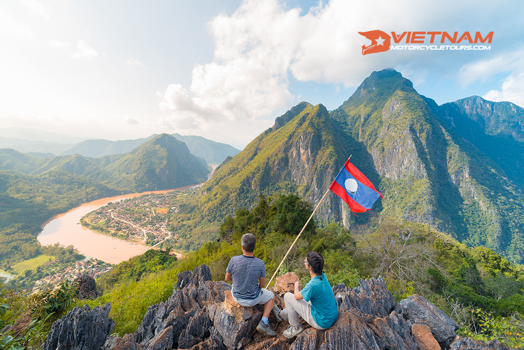 Motorbike Tours Laos 6 couple conquering mountain top nong khiaw panoramic view nam ou river valley laos national flag scenic mountain landscape